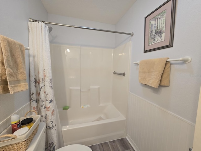 full bath with shower / bathtub combination with curtain, toilet, wood finished floors, and wainscoting