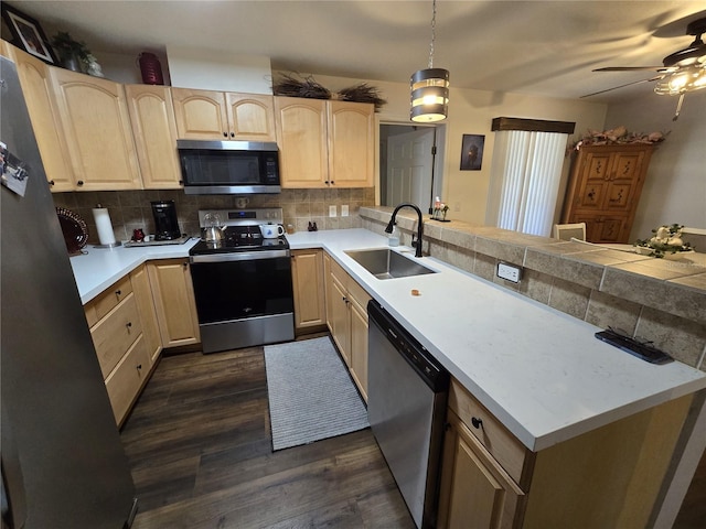 kitchen with backsplash, light brown cabinets, a peninsula, stainless steel appliances, and a sink