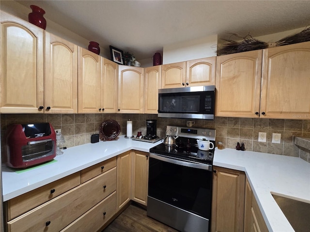 kitchen with light brown cabinetry, stainless steel microwave, backsplash, and electric stove