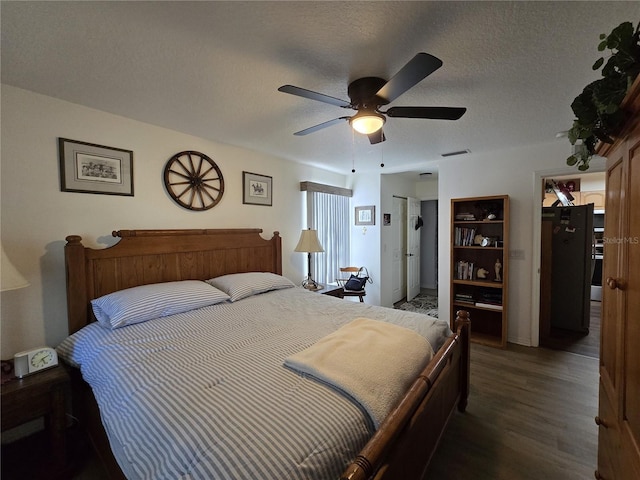 bedroom featuring visible vents, a textured ceiling, ceiling fan, and wood finished floors