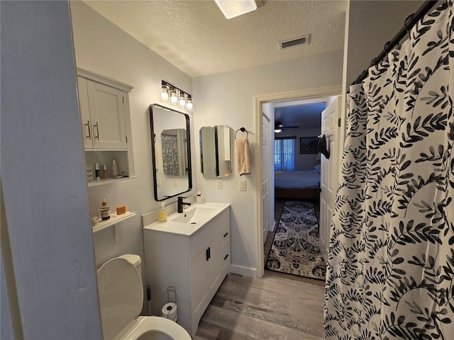 full bath featuring visible vents, toilet, a textured ceiling, wood finished floors, and vanity