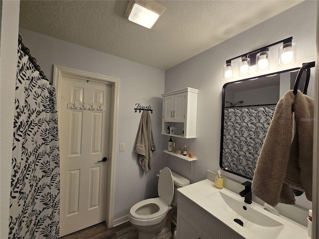 bathroom featuring a textured ceiling, toilet, vanity, and wood finished floors