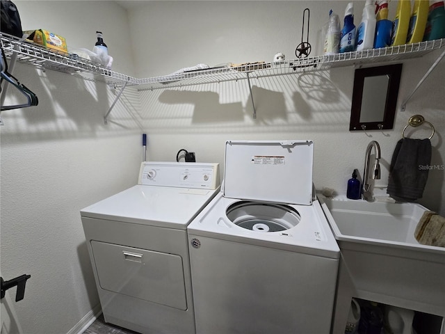 washroom featuring laundry area, washing machine and dryer, and a sink