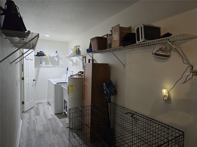 laundry room featuring washing machine and clothes dryer, light wood finished floors, electric water heater, laundry area, and a textured ceiling