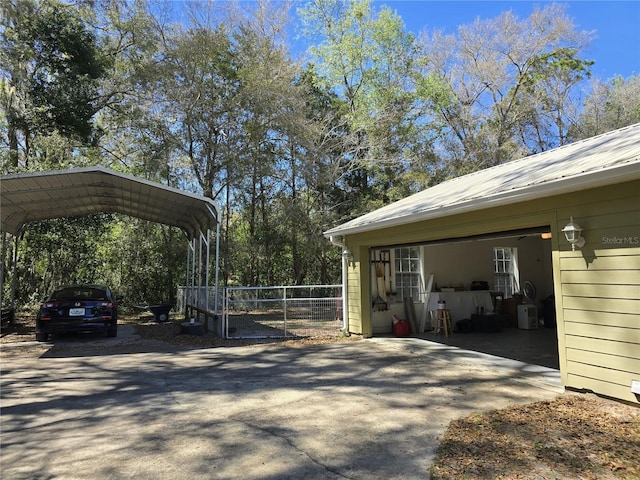 exterior space with a detached carport, driveway, and fence