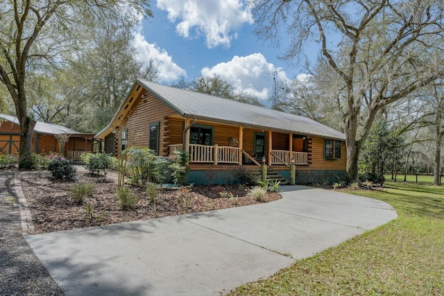 log-style house featuring a porch, log siding, and a front yard