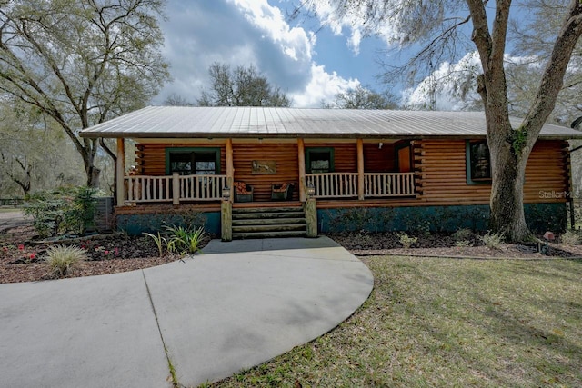 log cabin with log siding, covered porch, and metal roof