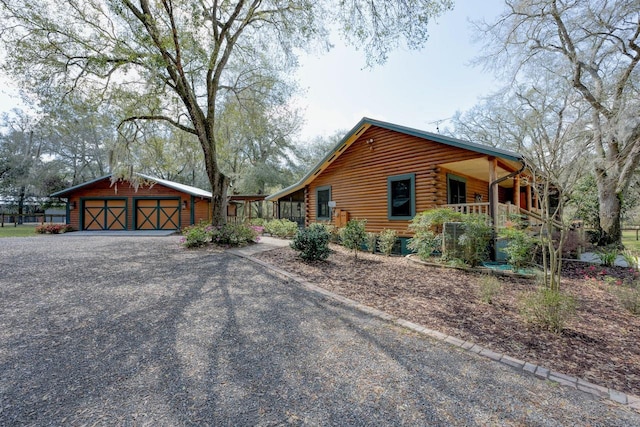 view of side of property featuring an outdoor structure, log exterior, and covered porch