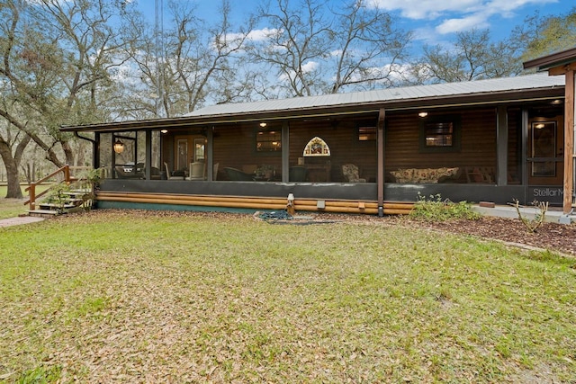 back of property with metal roof, a yard, and a sunroom