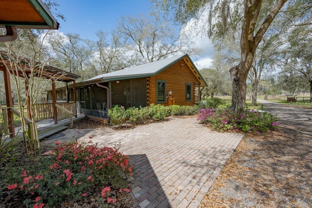 exterior space featuring log exterior and a sunroom