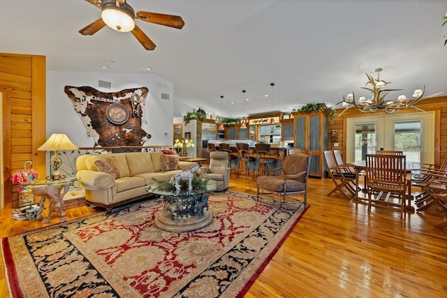 living room with visible vents, light wood-style flooring, vaulted ceiling, french doors, and ceiling fan with notable chandelier