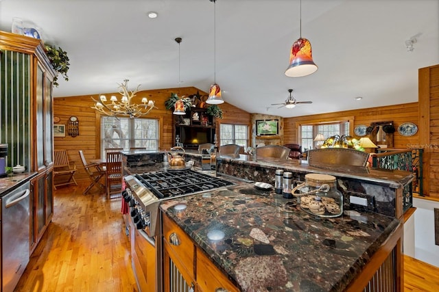 kitchen featuring wooden walls, lofted ceiling, light wood-style floors, pendant lighting, and open floor plan