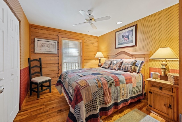 bedroom with wallpapered walls, a ceiling fan, and wood finished floors