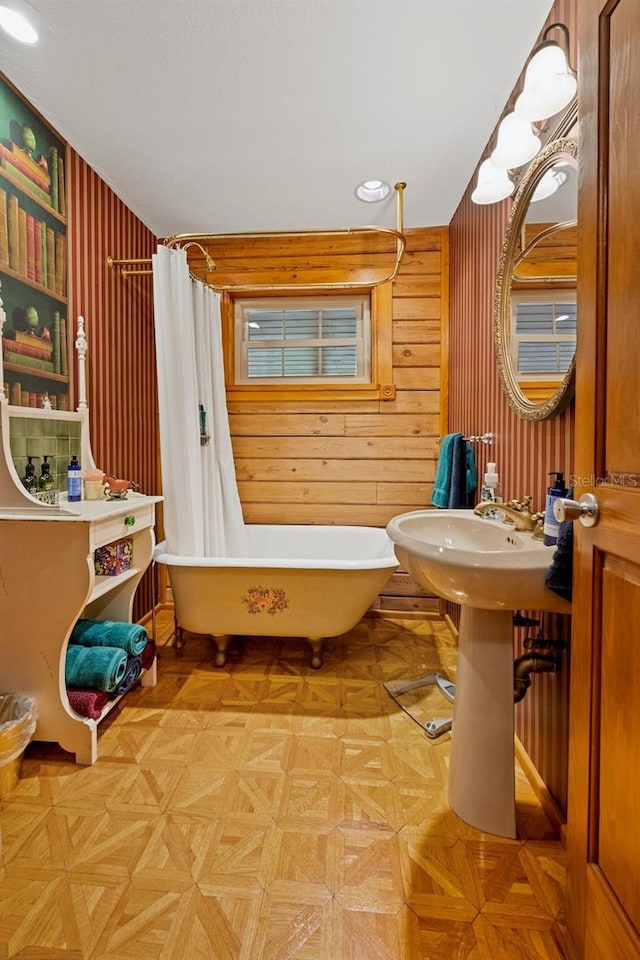 bathroom with curtained shower, a soaking tub, and wood walls