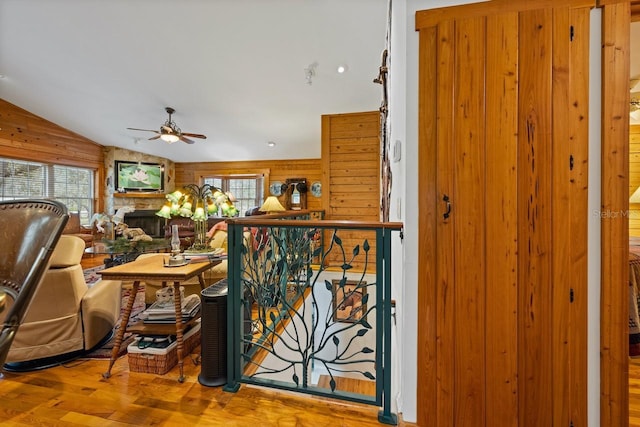 interior space featuring a stone fireplace, plenty of natural light, wood finished floors, and wood walls