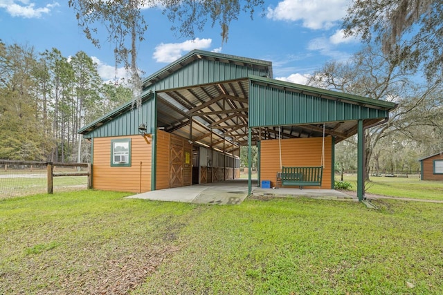 exterior space featuring a carport, board and batten siding, an outdoor structure, and a lawn