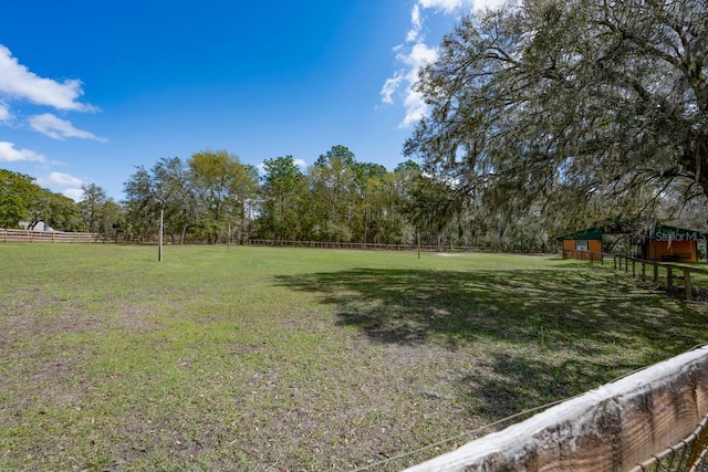 view of yard featuring a rural view, an outdoor structure, a storage shed, and fence