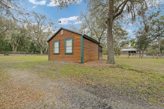 view of side of home with a yard, log veneer siding, and fence