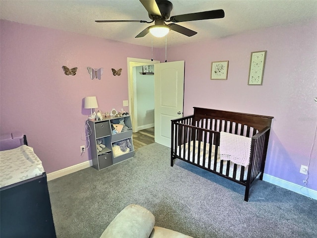 carpeted bedroom featuring ceiling fan, baseboards, and a nursery area