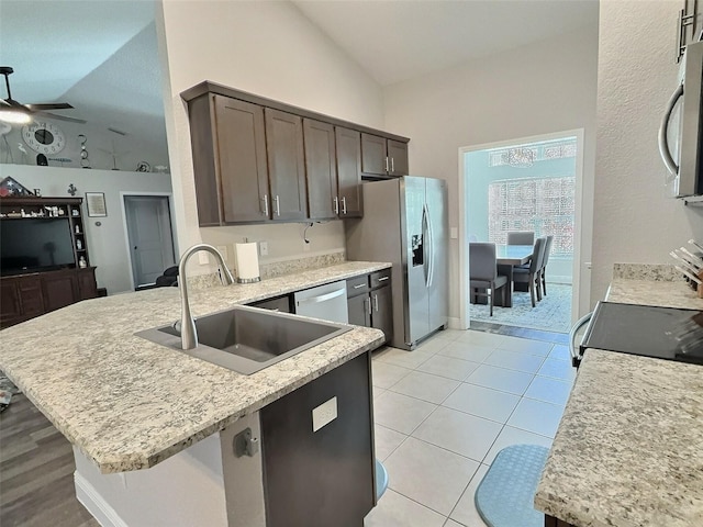 kitchen featuring a ceiling fan, a sink, appliances with stainless steel finishes, light tile patterned floors, and vaulted ceiling