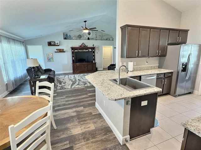 kitchen with vaulted ceiling, dark brown cabinets, stainless steel appliances, and a sink