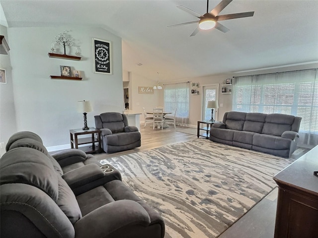 living area with baseboards, wood finished floors, ceiling fan, and vaulted ceiling