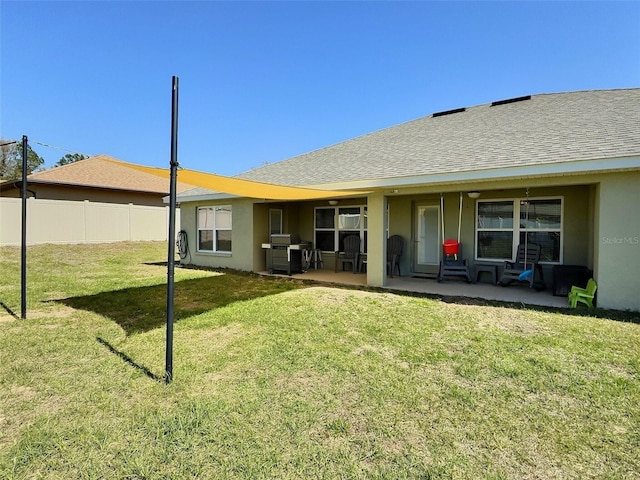 back of property with a patio area, a lawn, roof with shingles, and fence