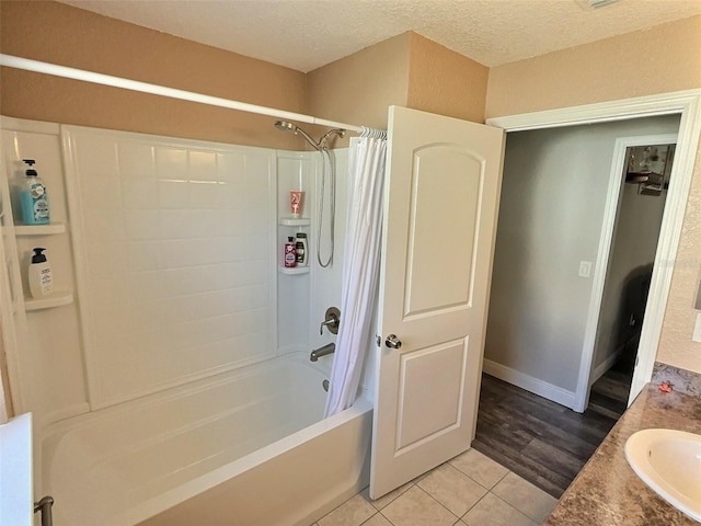 bathroom featuring baseboards, a sink, tile patterned flooring, shower / bath combination with curtain, and a textured ceiling