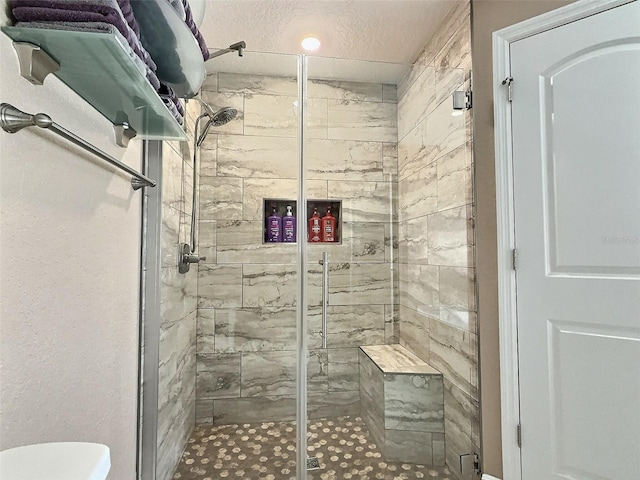 bathroom featuring a shower stall, a textured ceiling, and toilet