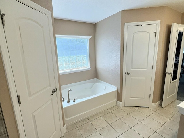 bathroom featuring baseboards, a bath, and tile patterned flooring