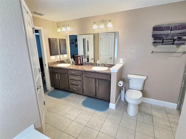 bathroom with double vanity, baseboards, tile patterned floors, and a sink