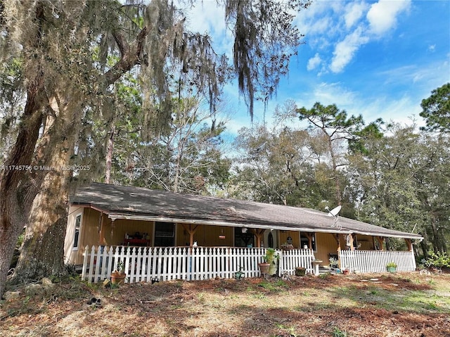 ranch-style house with a porch and fence