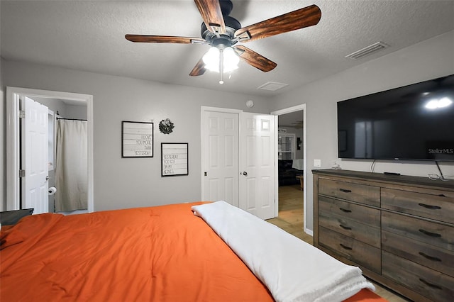 bedroom featuring visible vents, wood finished floors, a textured ceiling, and ceiling fan