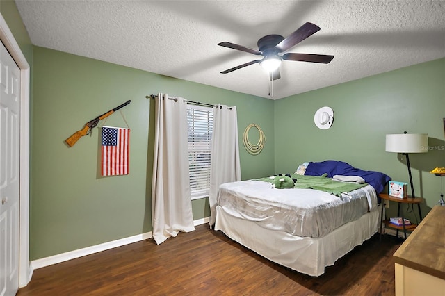 bedroom featuring ceiling fan, a textured ceiling, baseboards, and dark wood-style flooring