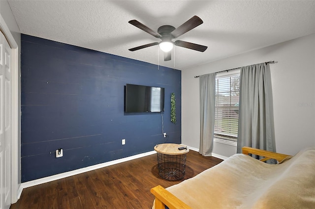 unfurnished bedroom with ceiling fan, wood finished floors, baseboards, and a textured ceiling