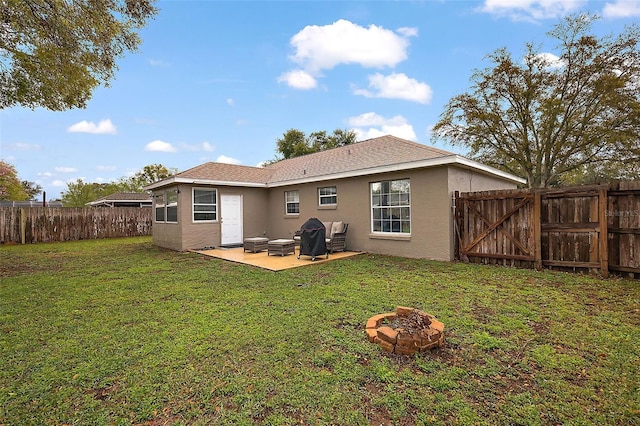 back of property with an outdoor fire pit, stucco siding, a yard, a fenced backyard, and a patio