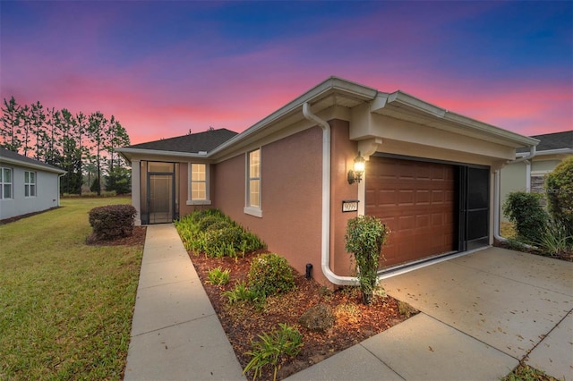 view of front of property with a yard, stucco siding, driveway, and a garage