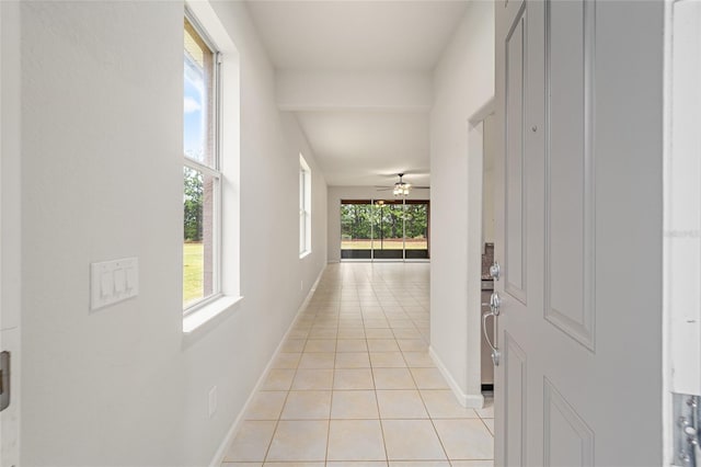 hall featuring light tile patterned flooring and baseboards