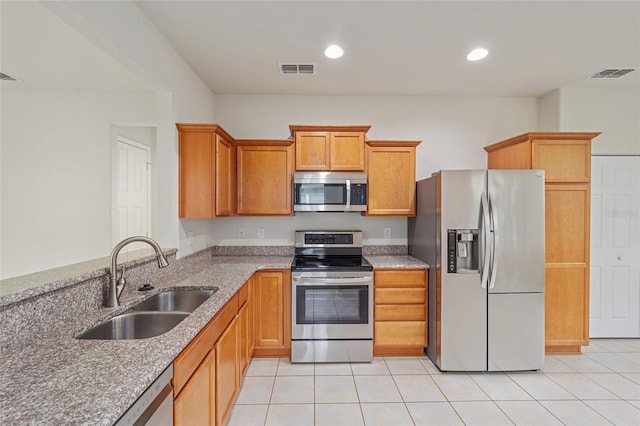 kitchen featuring light stone counters, visible vents, appliances with stainless steel finishes, and a sink