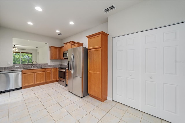 kitchen featuring light tile patterned floors, visible vents, brown cabinets, and stainless steel appliances