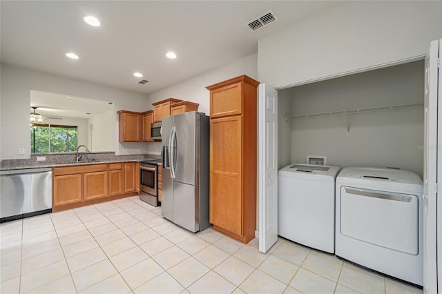 kitchen featuring visible vents, washer and dryer, appliances with stainless steel finishes, brown cabinetry, and light tile patterned floors