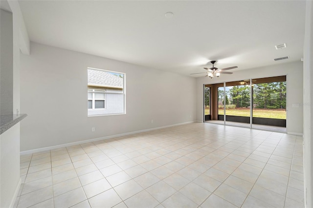 empty room featuring light tile patterned floors, visible vents, baseboards, and ceiling fan