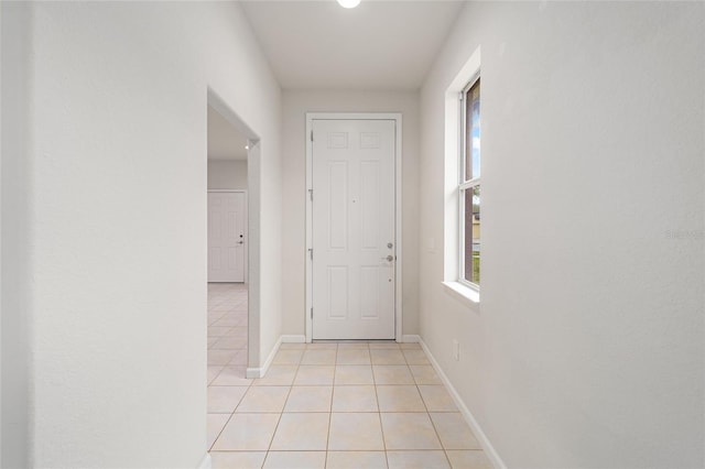 hallway with baseboards and light tile patterned flooring