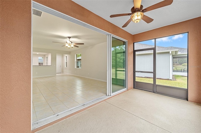 unfurnished sunroom with a ceiling fan, a healthy amount of sunlight, and visible vents