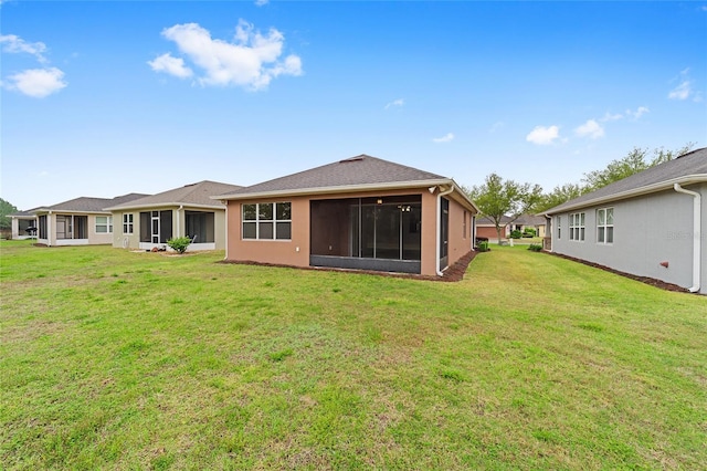 rear view of property with a yard, a sunroom, and stucco siding