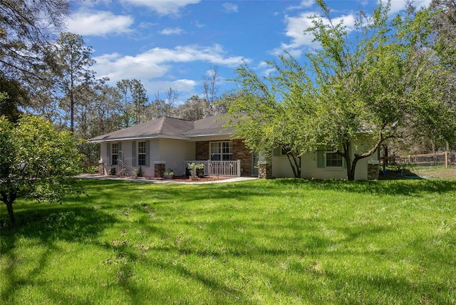 back of property with a yard, stone siding, and stucco siding