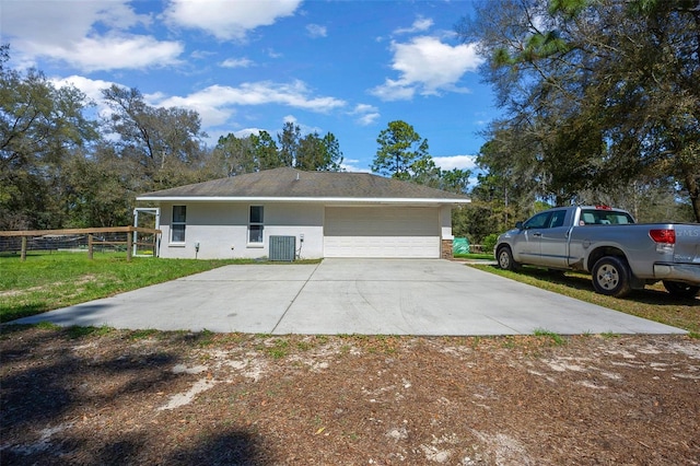 view of front of property with fence, an attached garage, central AC, stucco siding, and concrete driveway