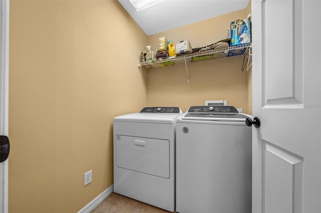 clothes washing area featuring laundry area, washing machine and dryer, baseboards, and a textured ceiling