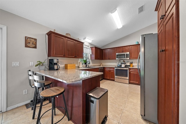 kitchen featuring a breakfast bar area, visible vents, a peninsula, a sink, and stainless steel appliances