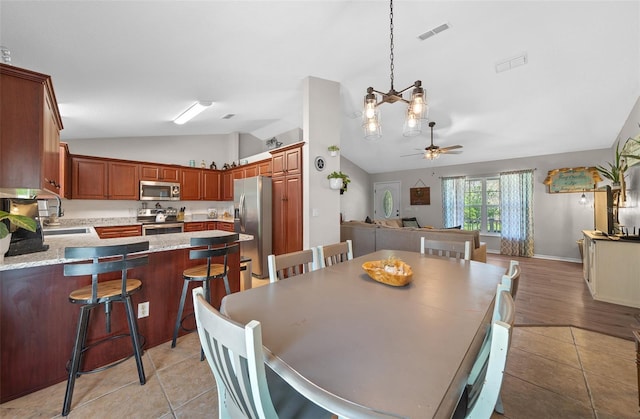 dining space featuring visible vents, light tile patterned flooring, a ceiling fan, and vaulted ceiling